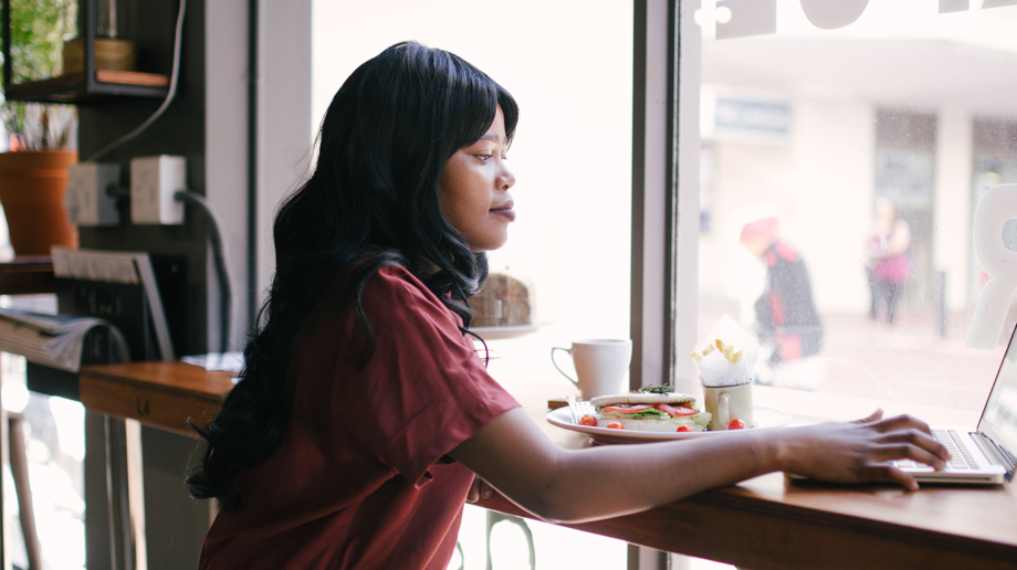 woman in red blouse at coffee shop working on her laptop