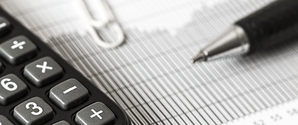 photo of a calculator, paperclip, and pen