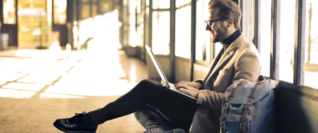 blonde man with glasses smiling at laptop