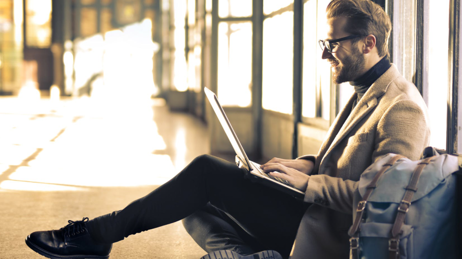 blonde man with glasses smiling at laptop