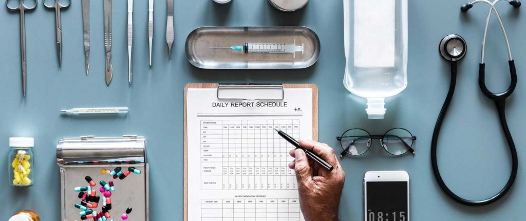 photo of healthcare materials like scissors, phone, paperwork, pills, etc.