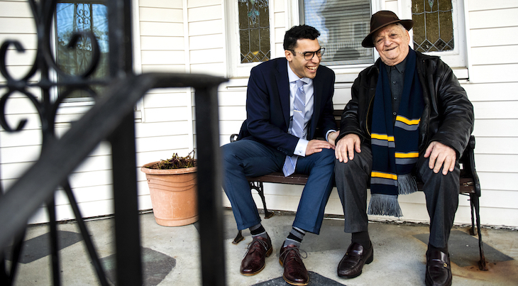 Emilio Guido and Theo Orphanos laughing sitting side by side laughing on Theo's porch.