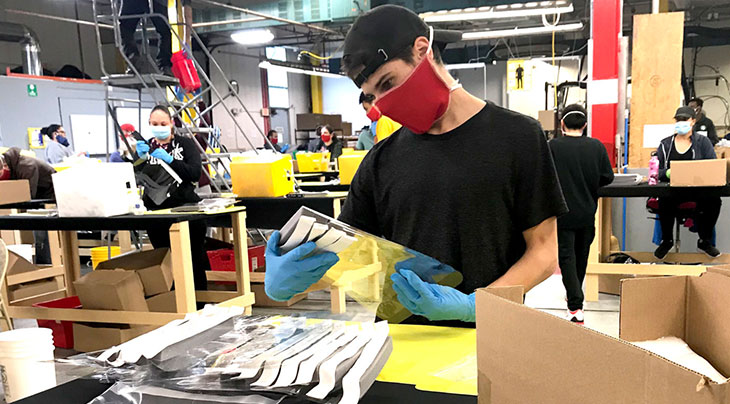 masked worker making plastic face shields