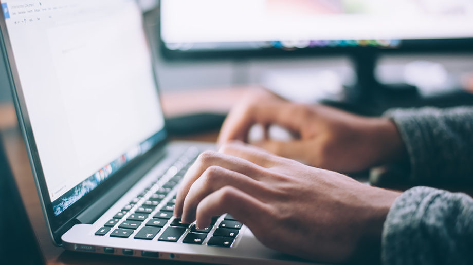 Photograph of someone typing on their laptop