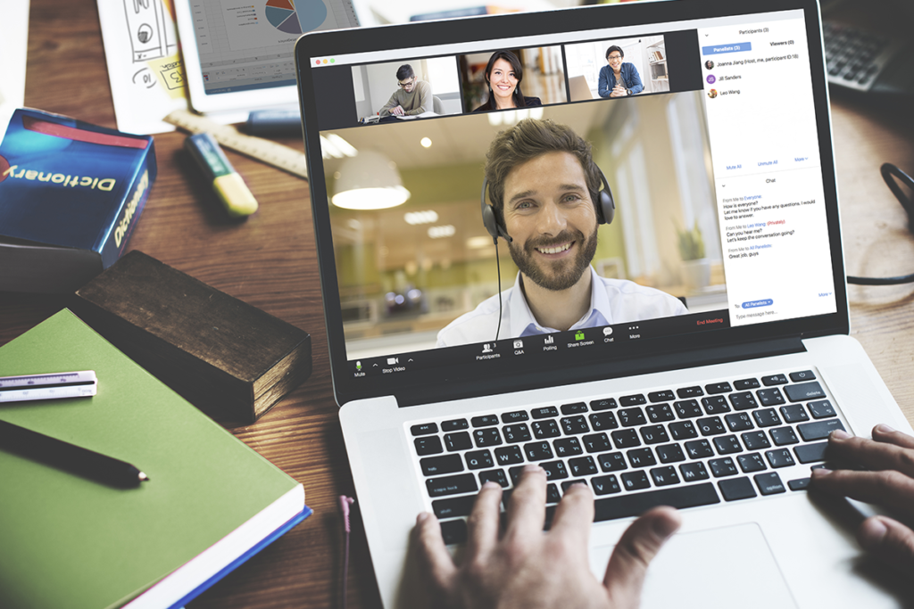 Photograph of a computer screen where a man can be seen smiling on Zoom