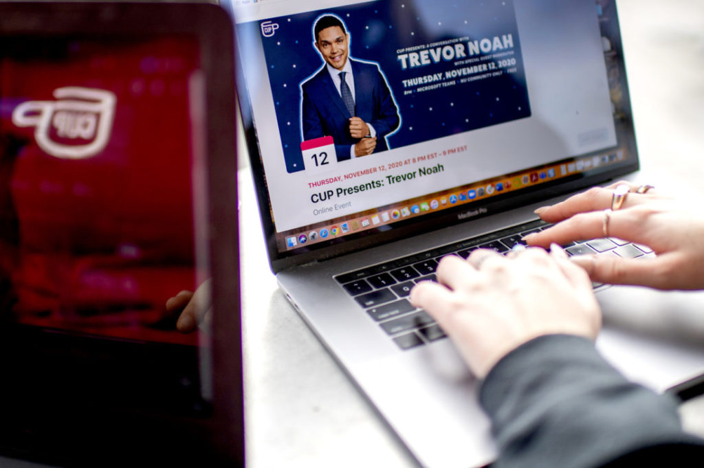 photo of someone typing on their laptop and the computer screen has a picture of Trevor Noah