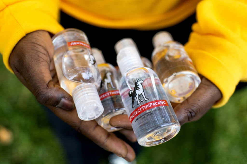 photo of someone holding bottles of hand sanitizers branded with #protectthepacknu