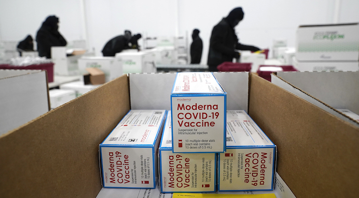 Photograph of a packaging facility featuring boxes of the Moderna COVID-19 Vaccine