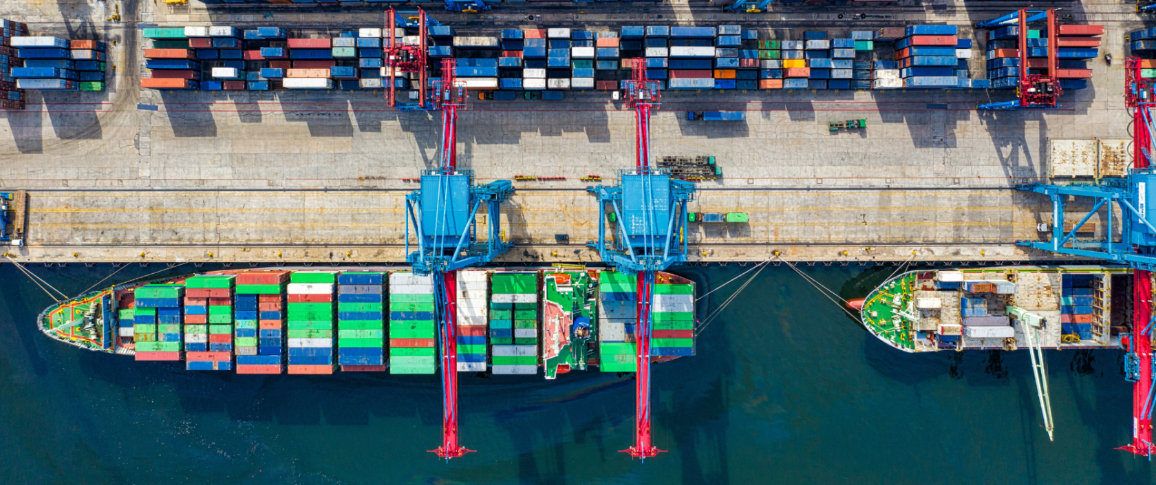 Photo of a dock where many cargo ships are being loaded with colorful shipping containers