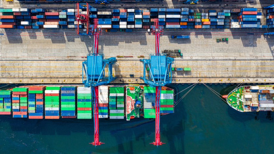 Photo of a dock where many cargo ships are being loaded with colorful shipping containers