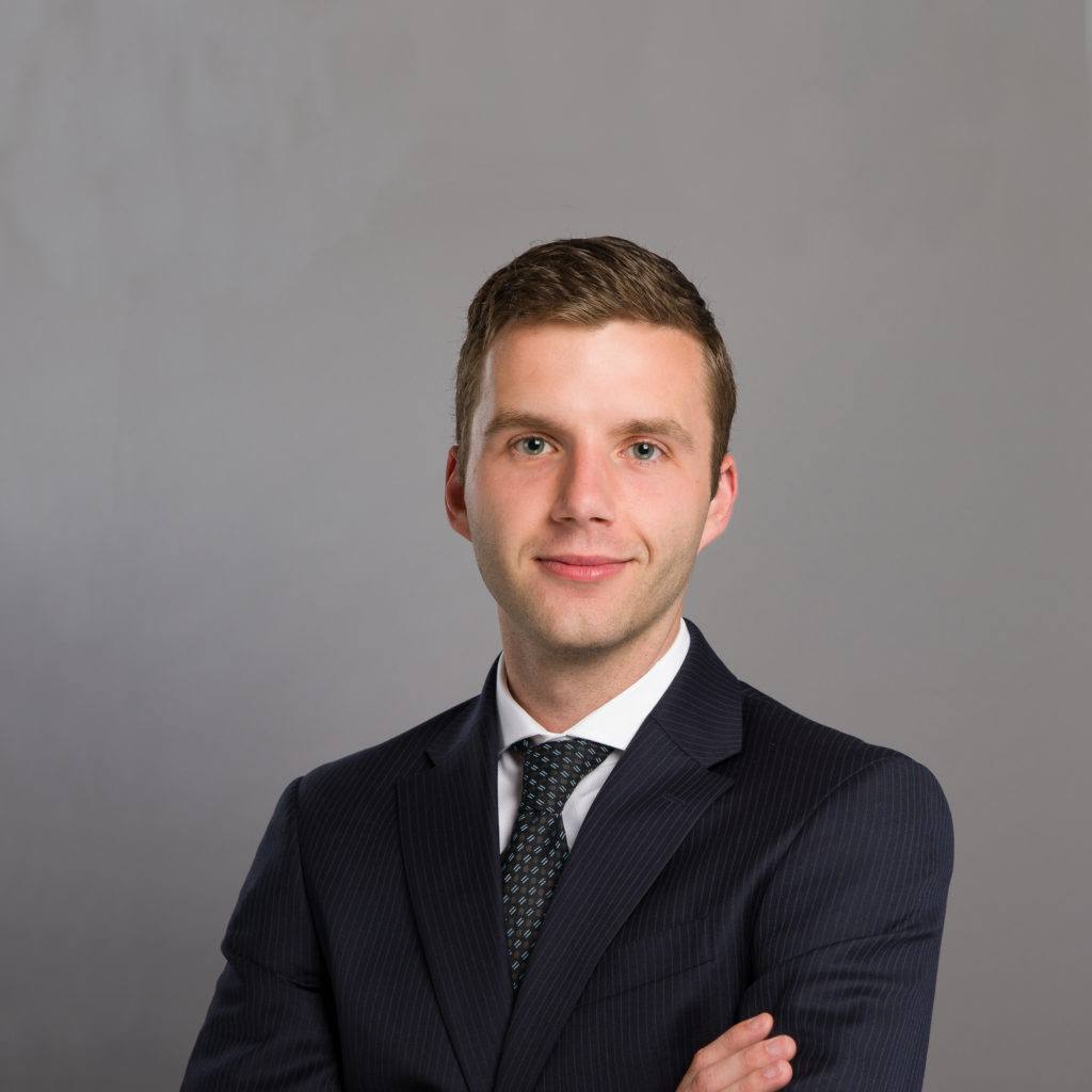 Photo of man smiling with arms crossed wearing a suit
