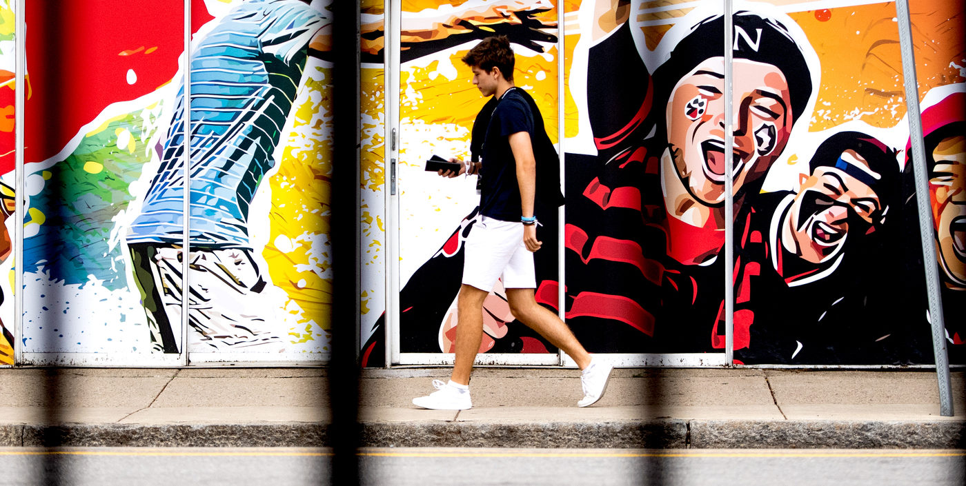 photo of a student walking along the sidewalk in front of a mural
