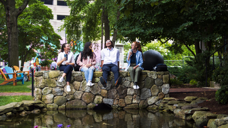 photo of northeastern students sitting on a stone wall talking