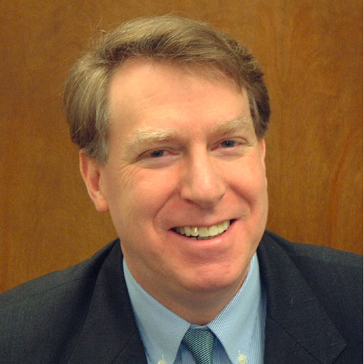 Headshot of Norman Jacknis wearing a blue shirt, tie, and blazer.