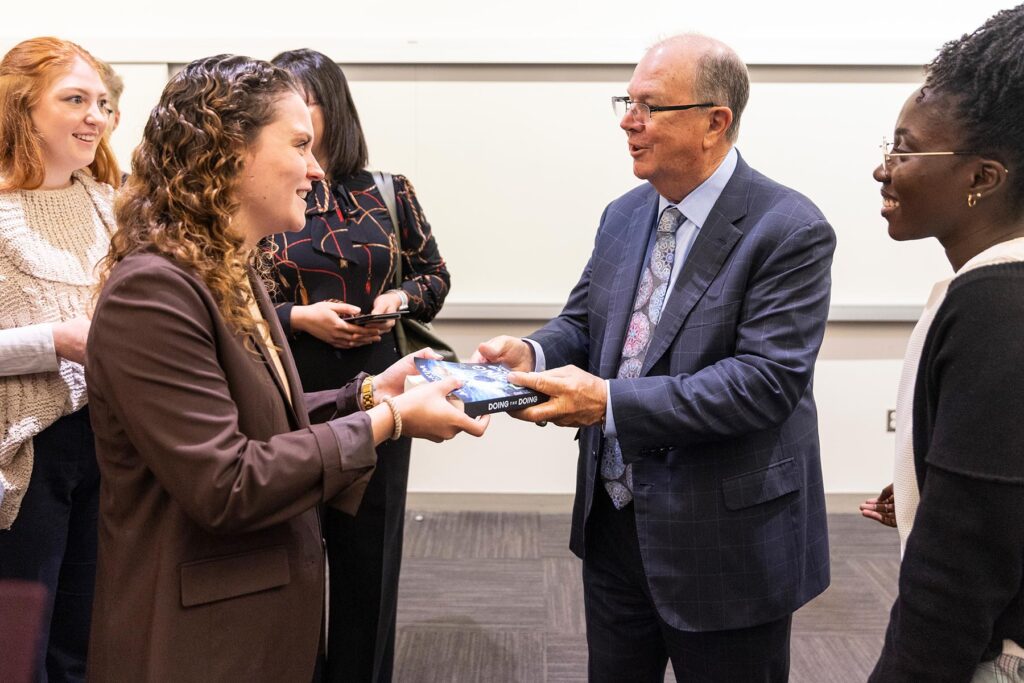 Alan McKim, MBA'88, exchanges his book "Doing the Doing" with a student.