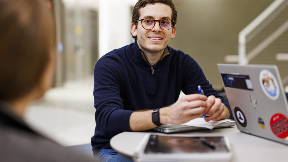 Student at a table with laptops and notebooks